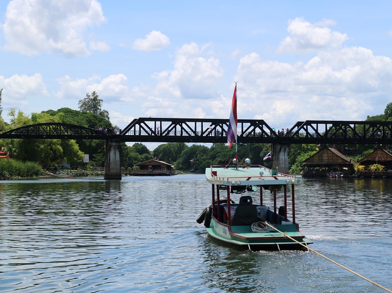 Boat passing under the bridge over the river Kwai